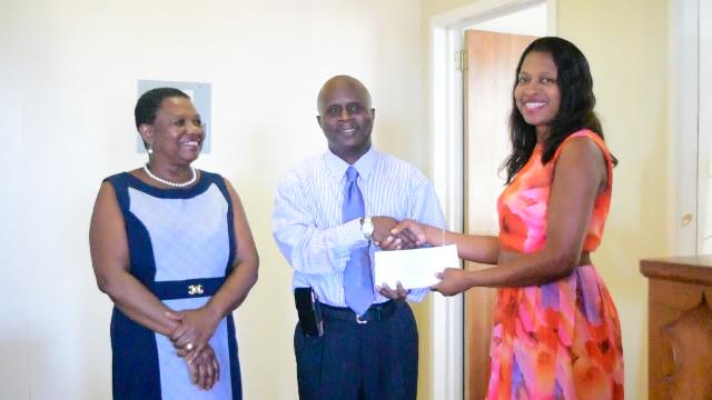 Permanent Secretary in the Ministry of Education Wakely Daniel accepting donations from Michele Pemberton, Treasurer of the Nevis Association of South Florida on behalf of her association and the Dr. Lornette Mills Charitable Fund at the Department of Education recently, while Palsy Wilkin, Principal Education Officer in the Nevis Island Administration looks on